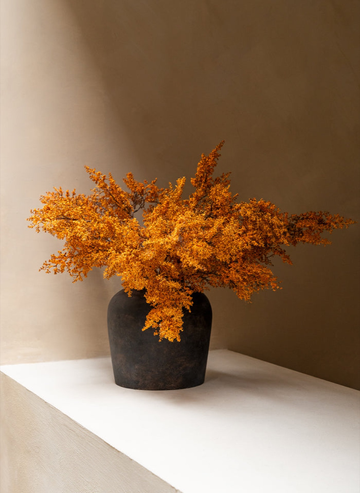 Oranje herfstbloemen in een donkere vaas